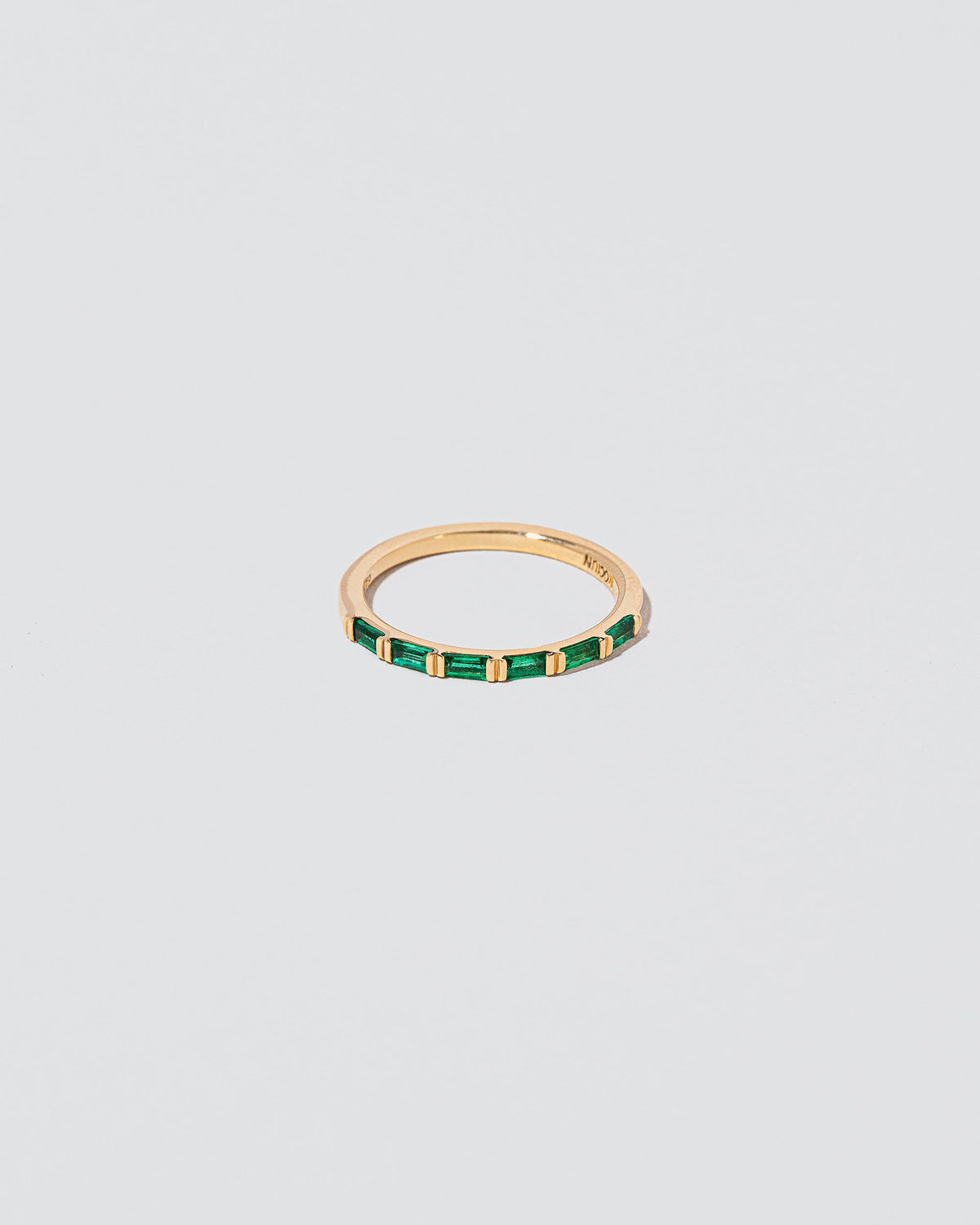 Gold Emerald Bar Baguette Band on light color background.