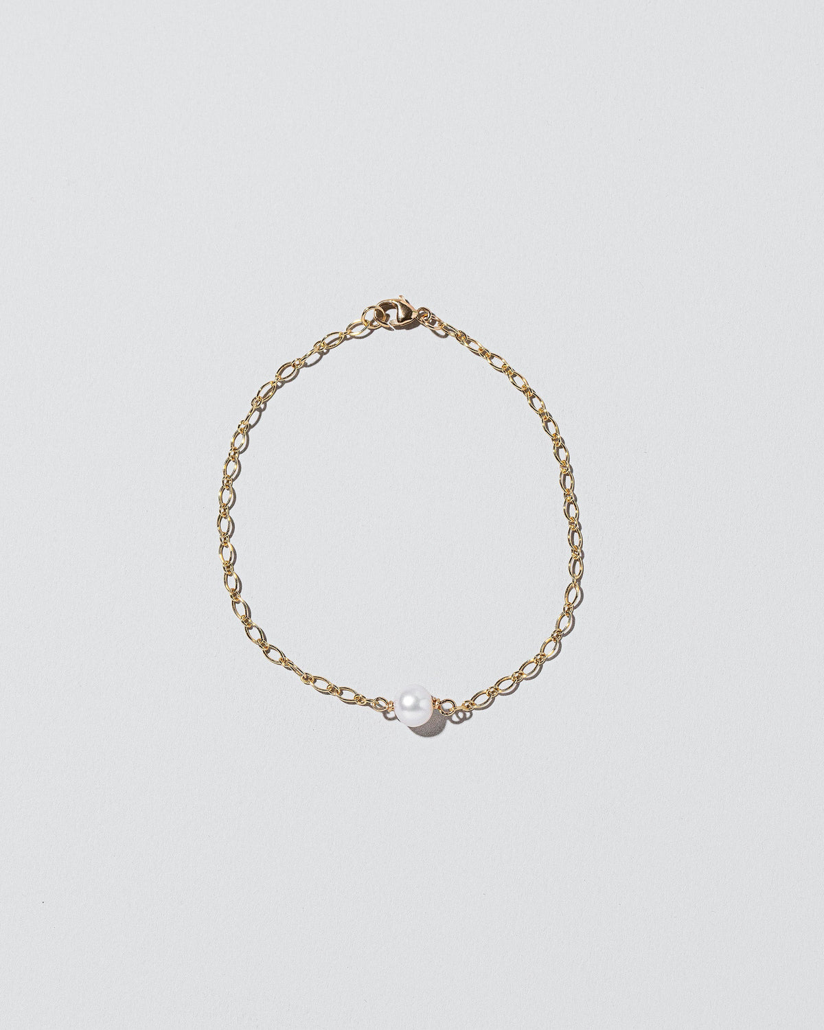 One Pearl Station Bracelet Open Oval Chain on light color background.