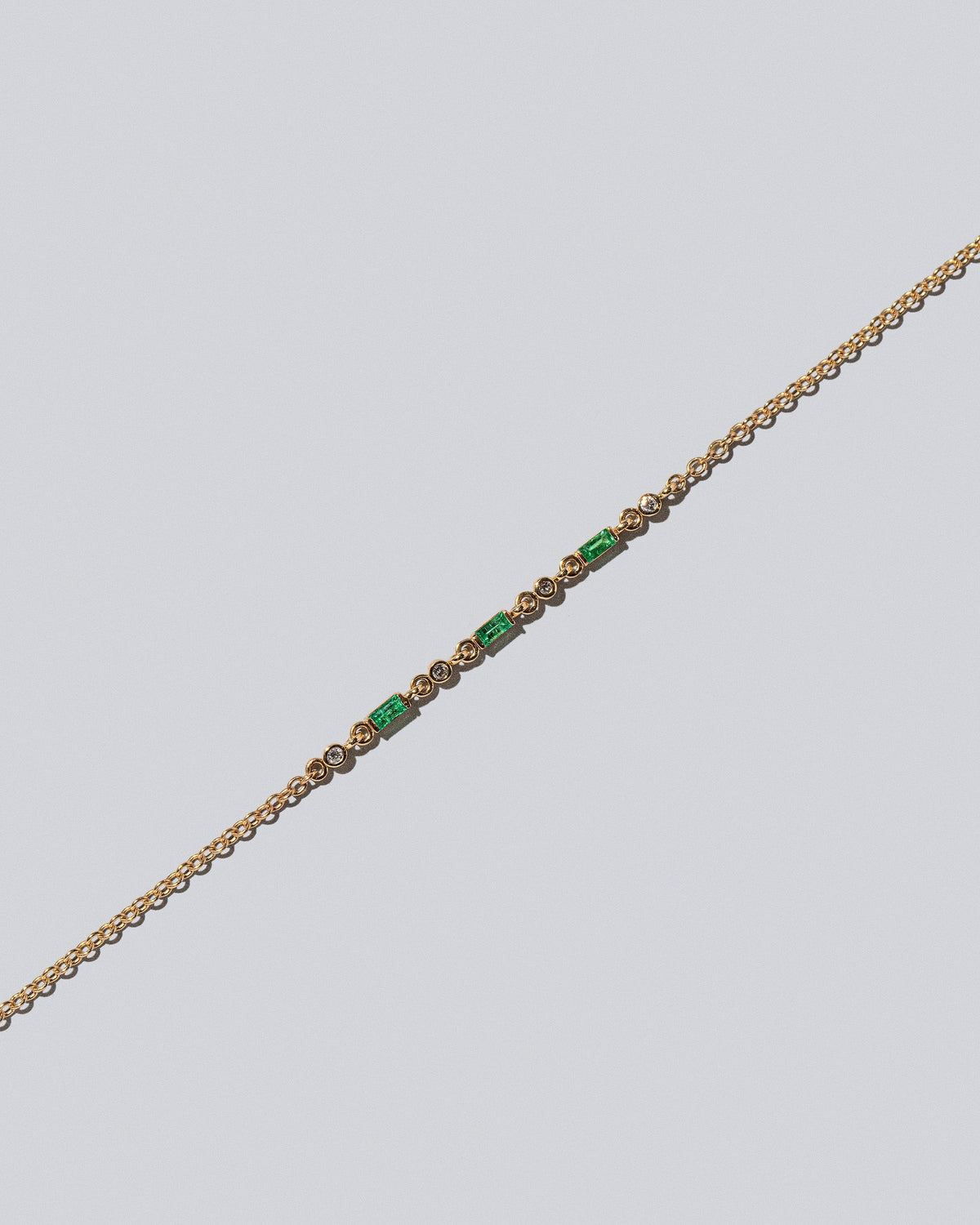 Closeup detail of the Emerald Consecutive Building Block Bracelet on light color background.