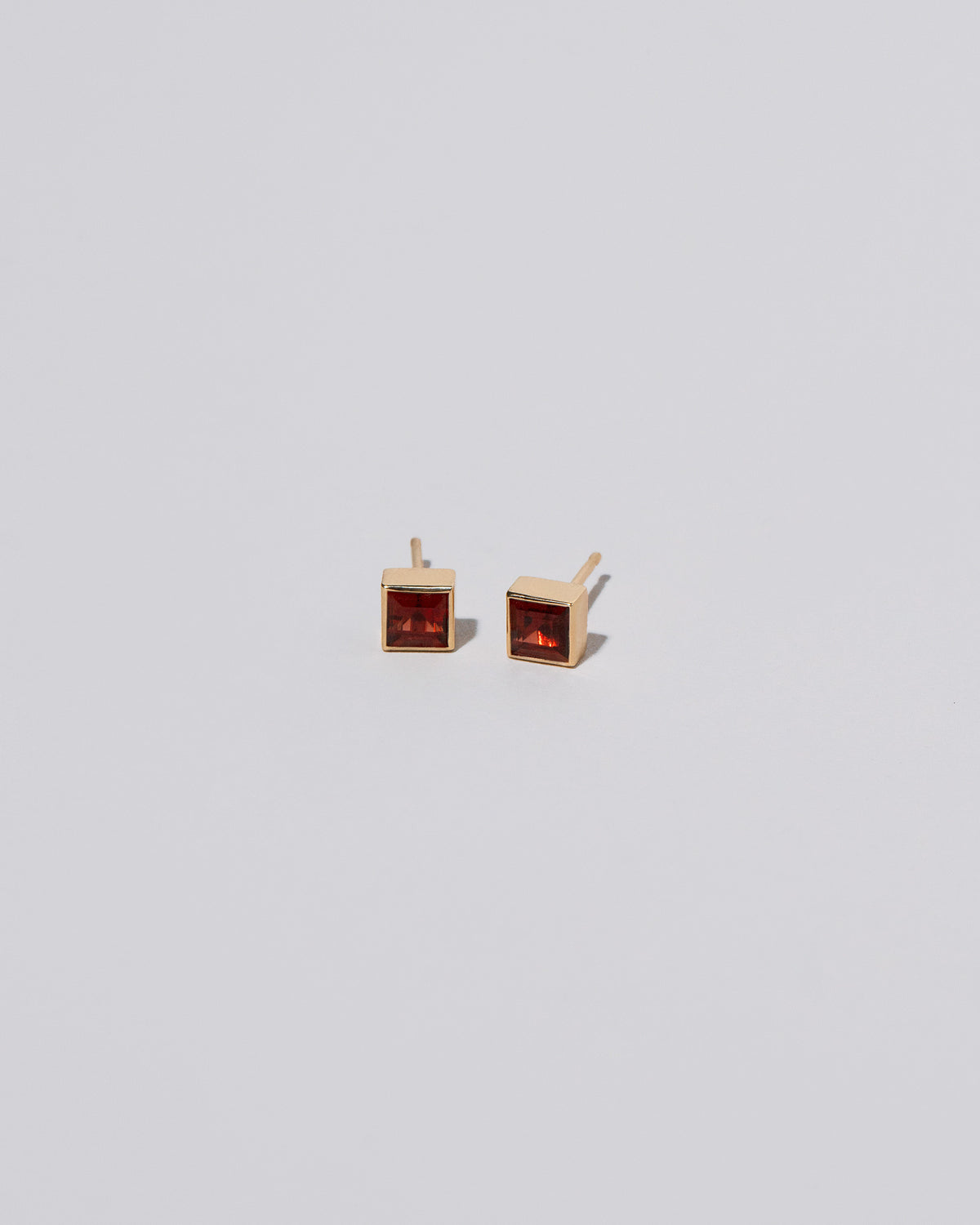 Square Frame Stud Earrings in Garnet on light color background.