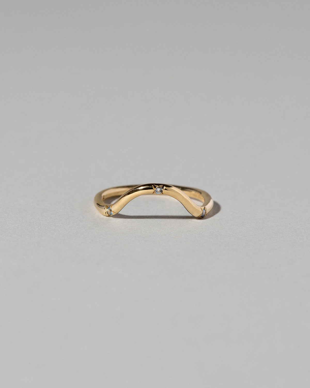 Gold Three Stone Blue Sapphire Curve Band on light color background.