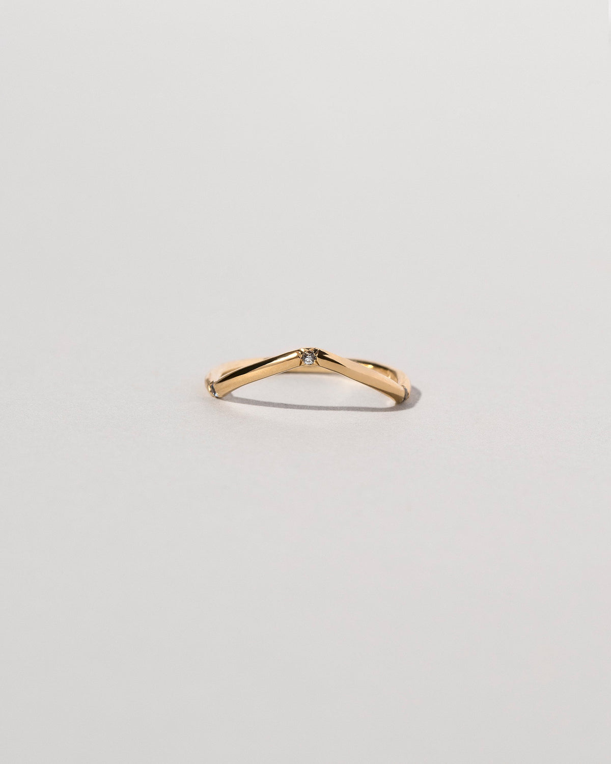 Gold Three Stone Blue Sapphire Low Peak Band on light color background.