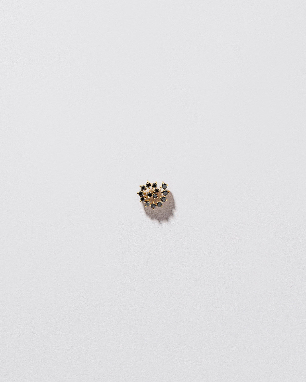 Mini Black Diamond Left Spiral Stud Earring Single on light color background.
