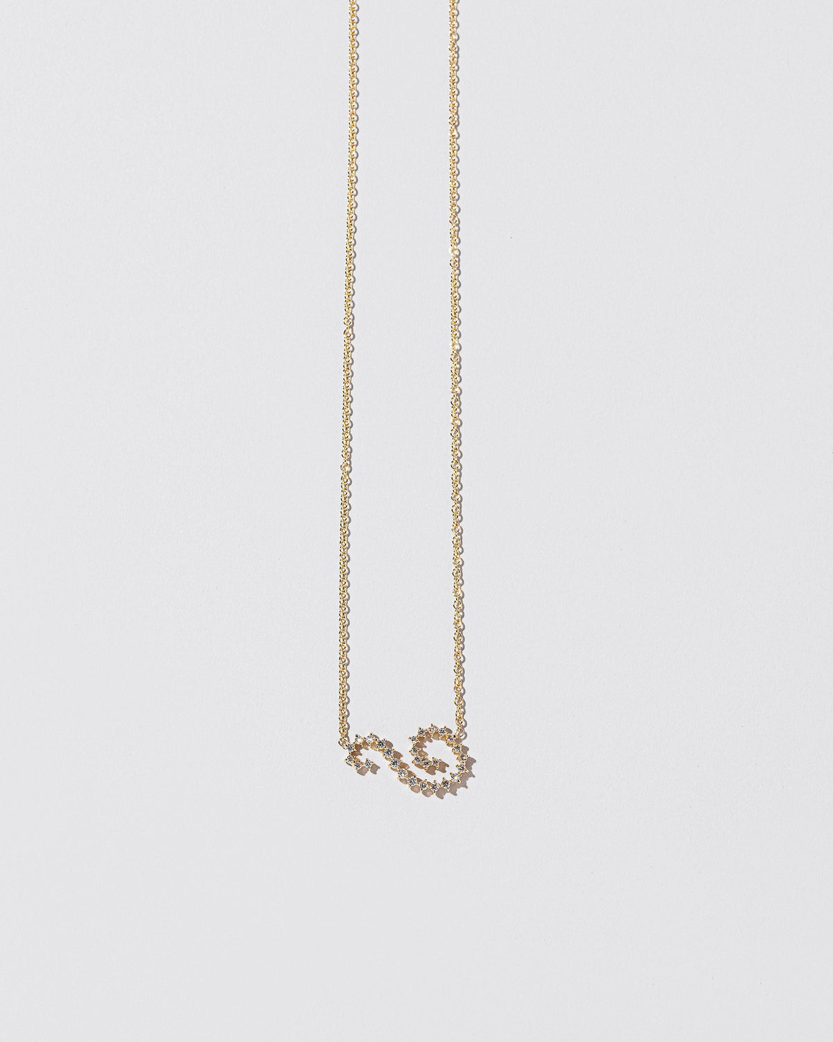 White Diamond Symbol of Change Necklace on light color background.