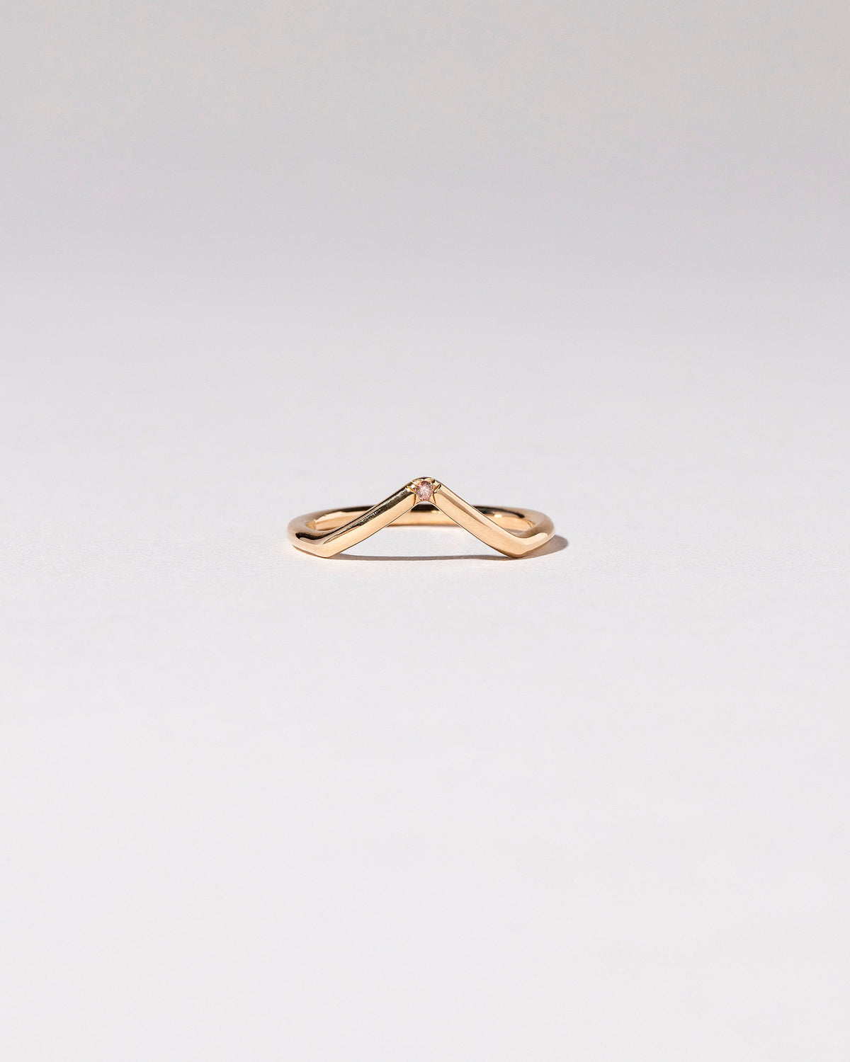 Gold Single Stone Peach Sapphire High Peak Band on light color background.