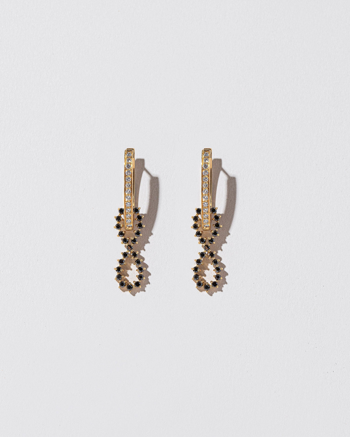 White Diamond and Black Diamond Lifecycle Earrings on light color background.