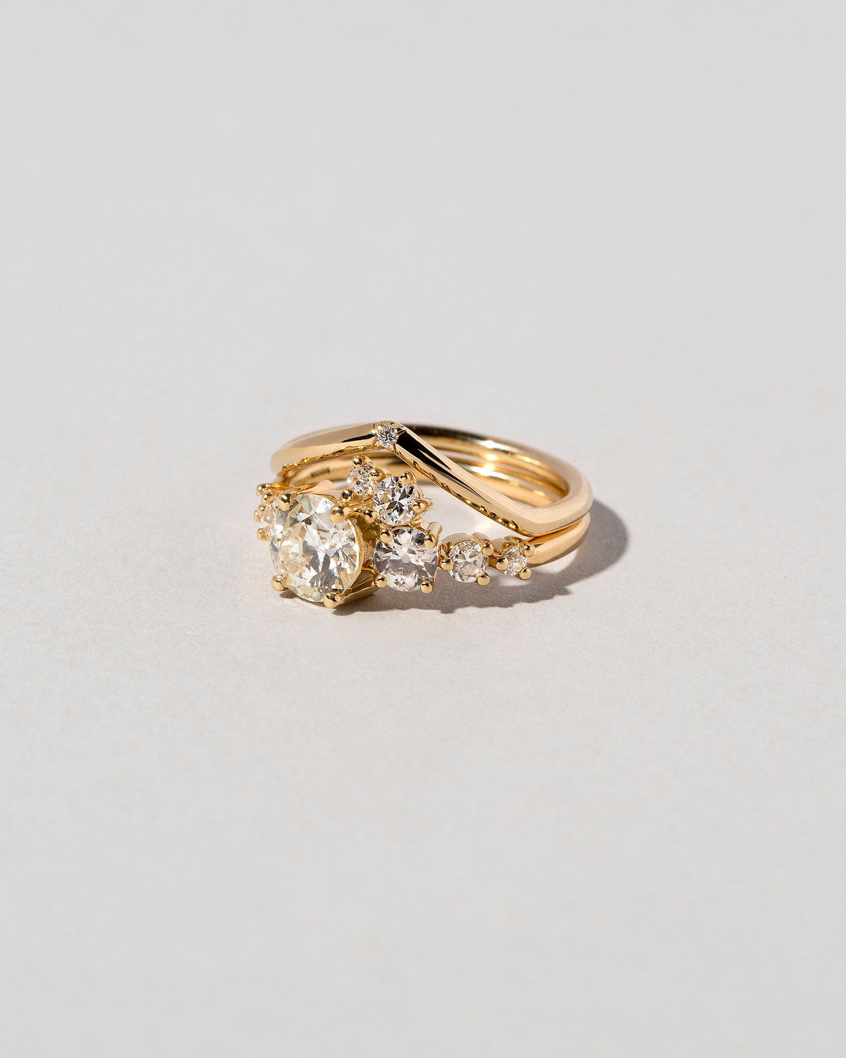 Gold White Diamond Single Stone Luna Peak Band and White Diamond Luna Ring on light color background.