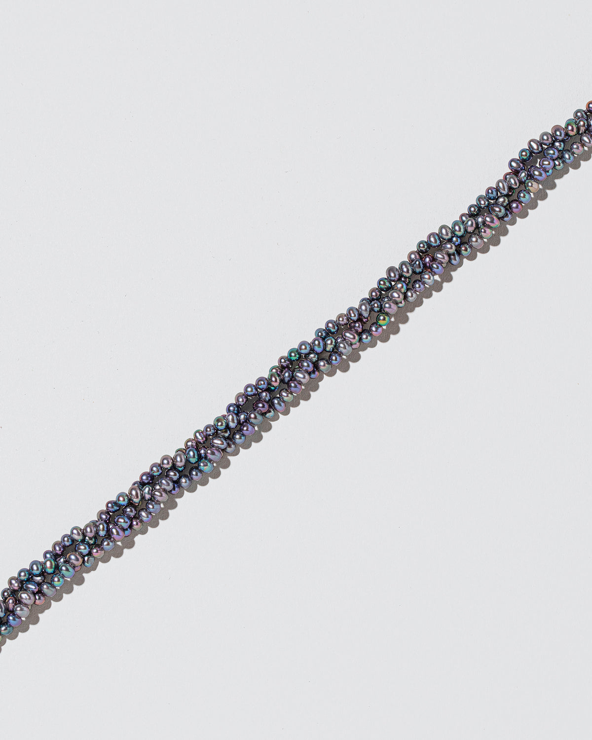 Closeup details of the Braided Seed Pearl Choker Necklace on light color background.