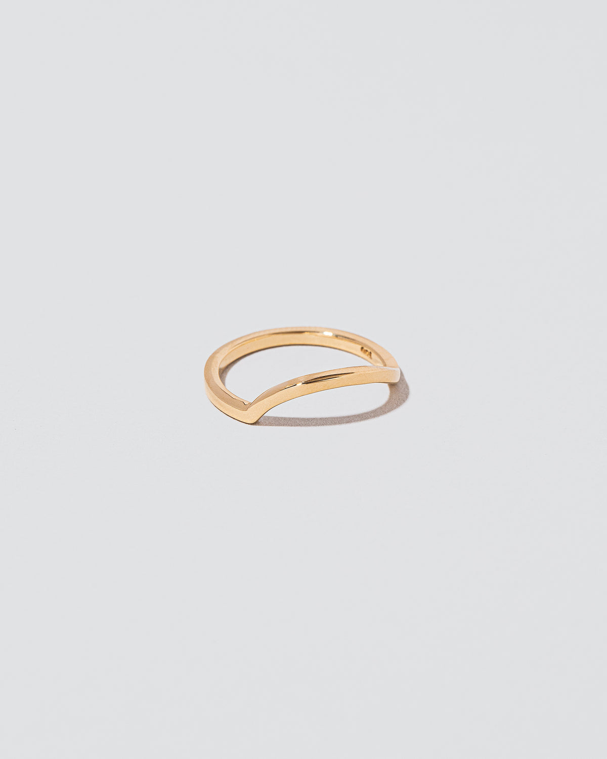 View from the side of the Gold Solid Square Wire Left Slump Band on light color background.