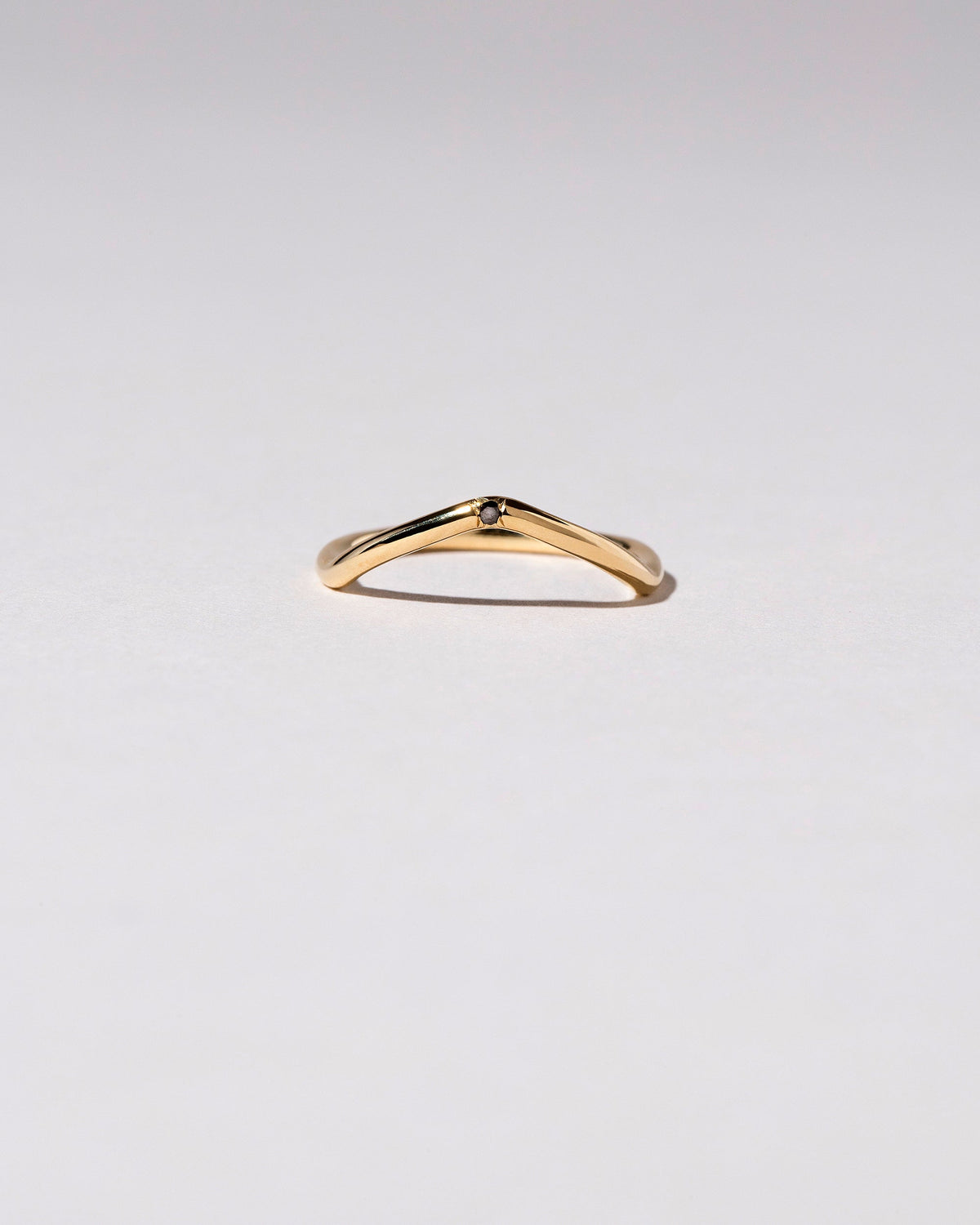 Gold Single Stone Black Diamond Low Peak Band on light color background.