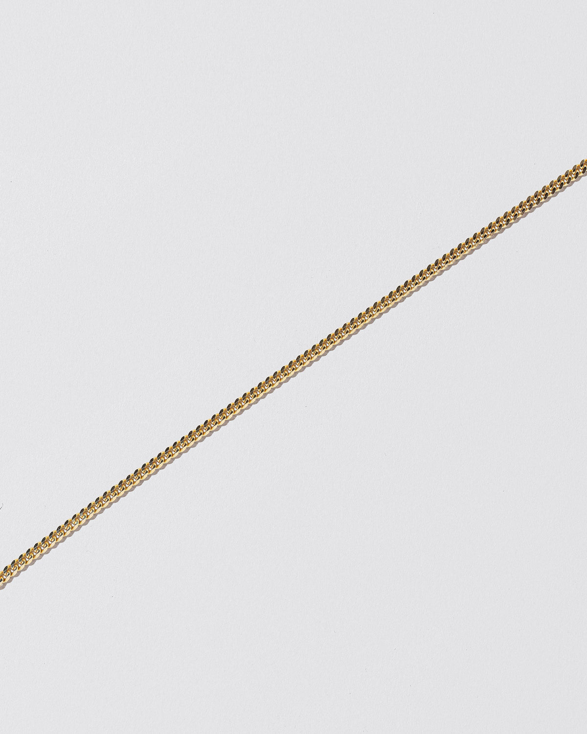 Closeup details of the 2.4mm Curb Chain Bracelet on light color background.