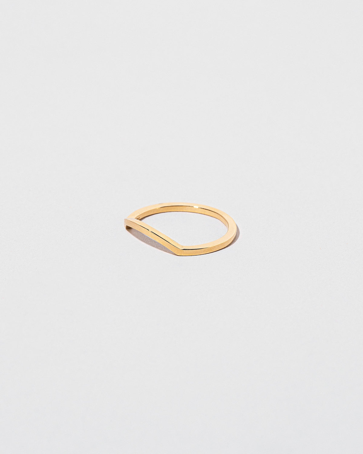 View from the side of the Gold Square Wire Mini Curve Band on light color background.