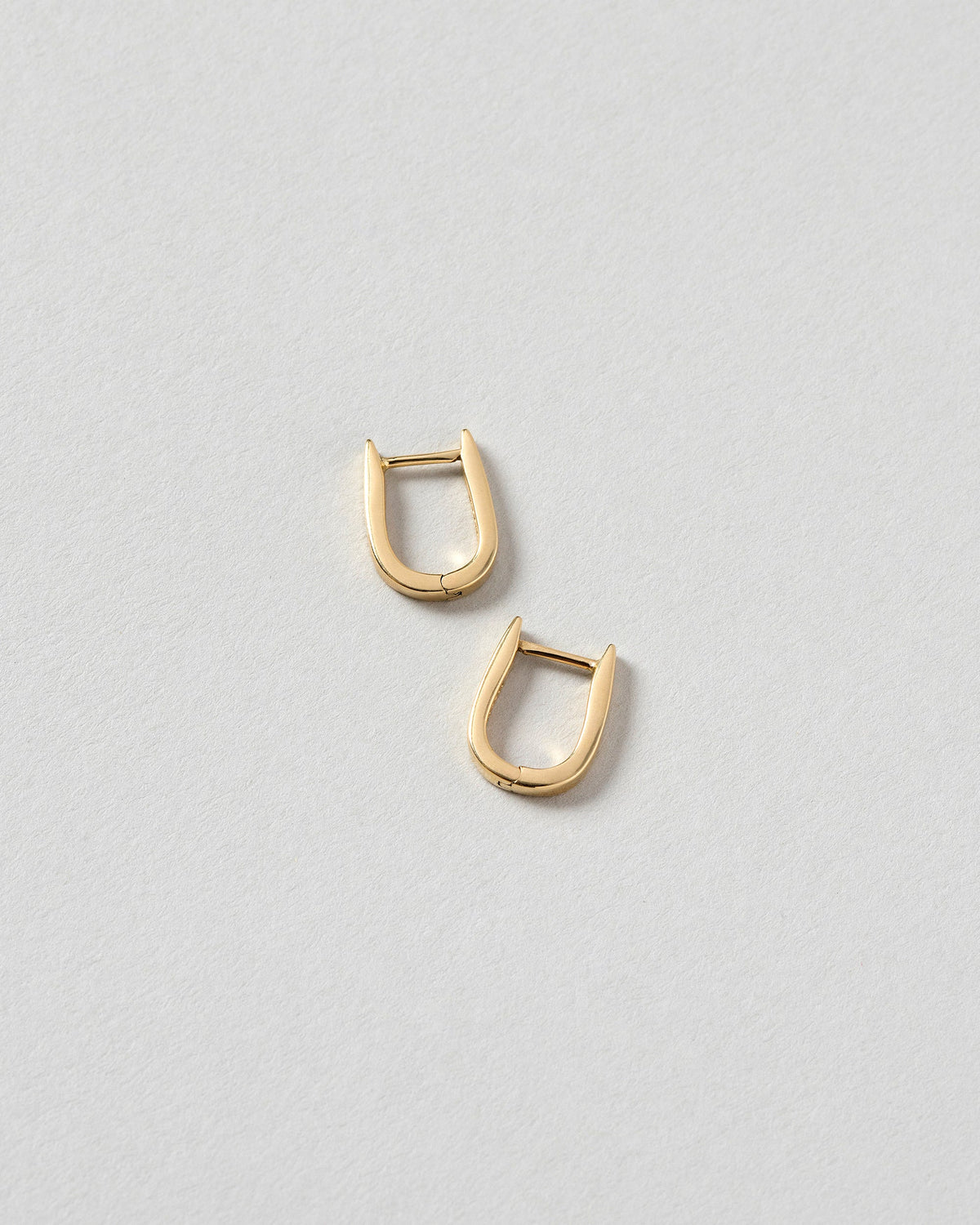 Poppy Flower Bud Huggie Hoop Earrings on light color background.