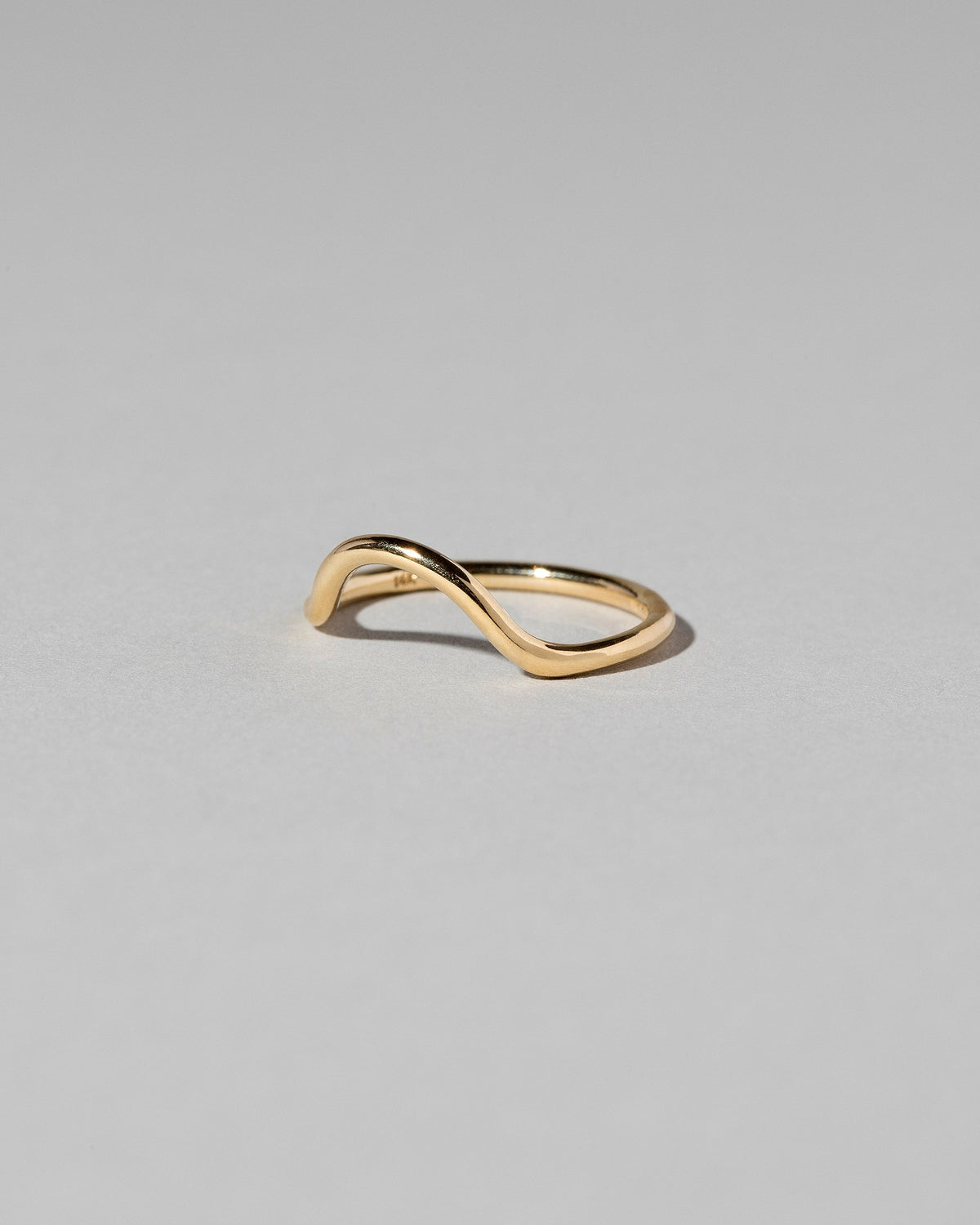 Closeup details of the Gold Solid Round Wire Curve Band on light color background.