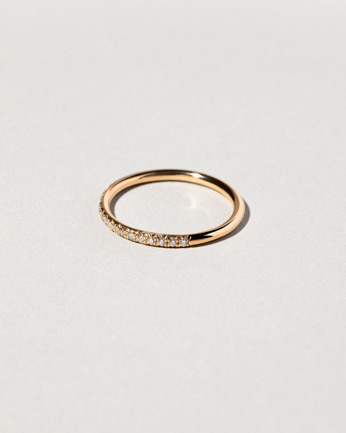 Closeup details of the Gold White Diamond Sapphire Fifteen Stone Dot Band on light color background.
