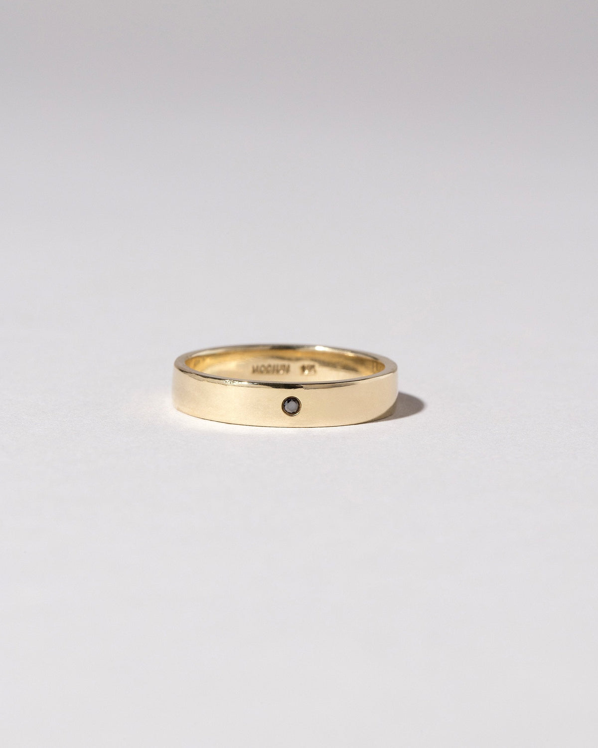 Closeup detail of the Gold 4mm Square Wire Band with Single Stone Black Diamond 1.6mm added on light color background.