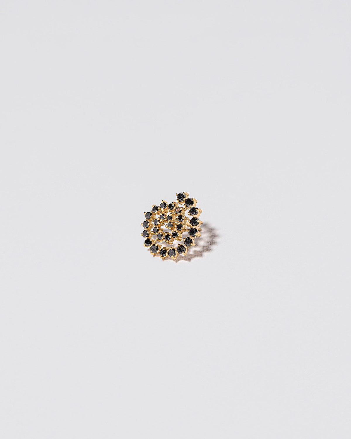 Closeup details of the Full Black Diamond Left Spiral Stud Earring Single on light color background.