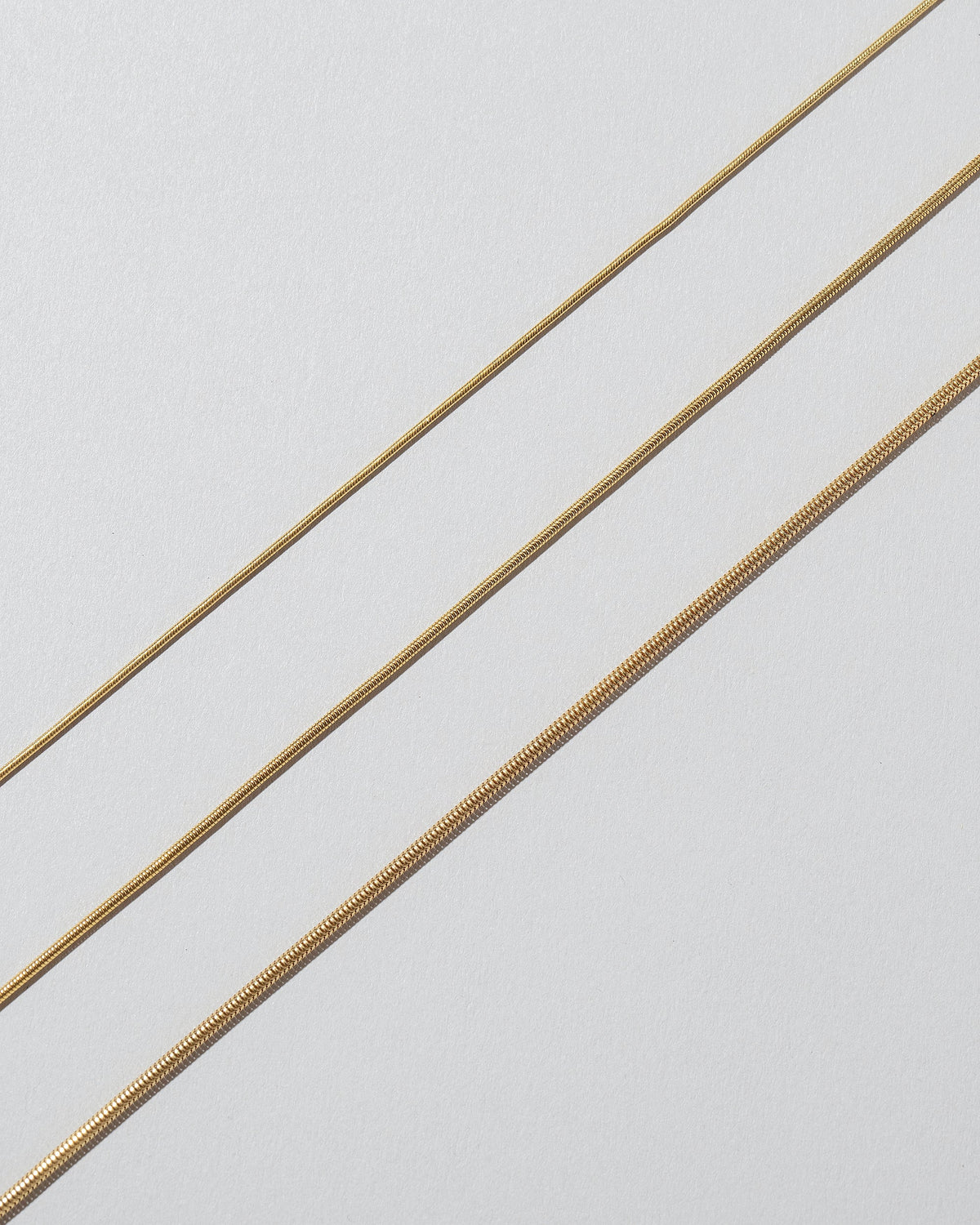 Closeup details of the 0.9mm Serpent Chain Necklace, 1.2mm Serpent Chain Necklace and 1.6mm Serpent Chain Necklace on light color background.