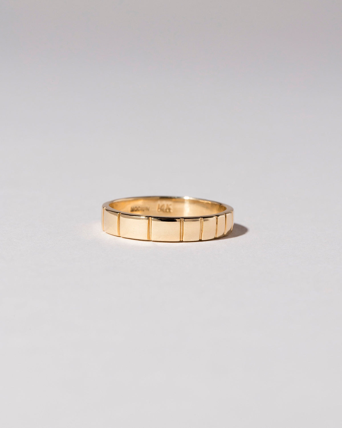 View from the side of the Gold 3mm Etched Lines Band on light color background.