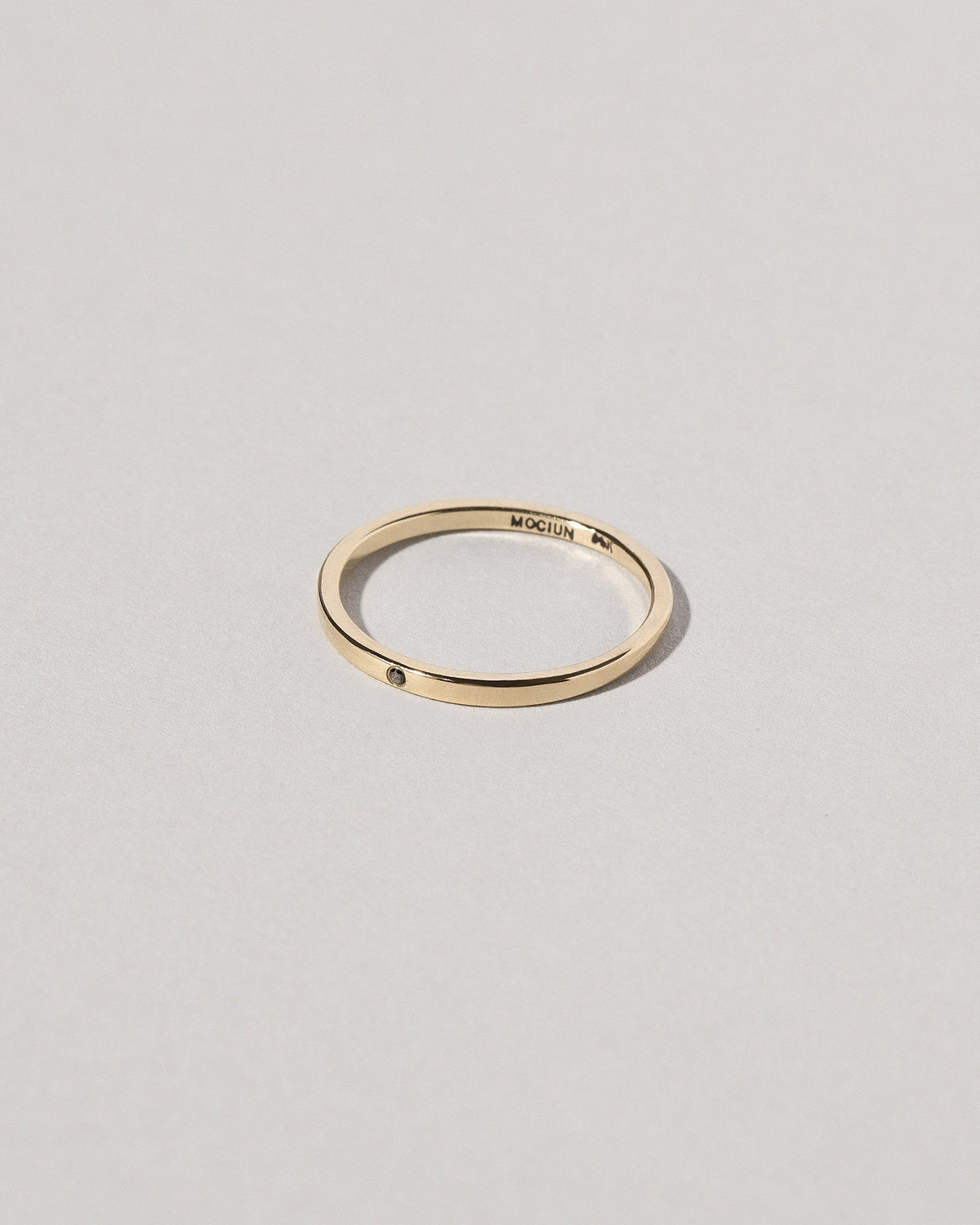 View from the side of the Gold 1.5mm Square Wire Band with Single Stone Black Diamond 1.3mm on light color background.